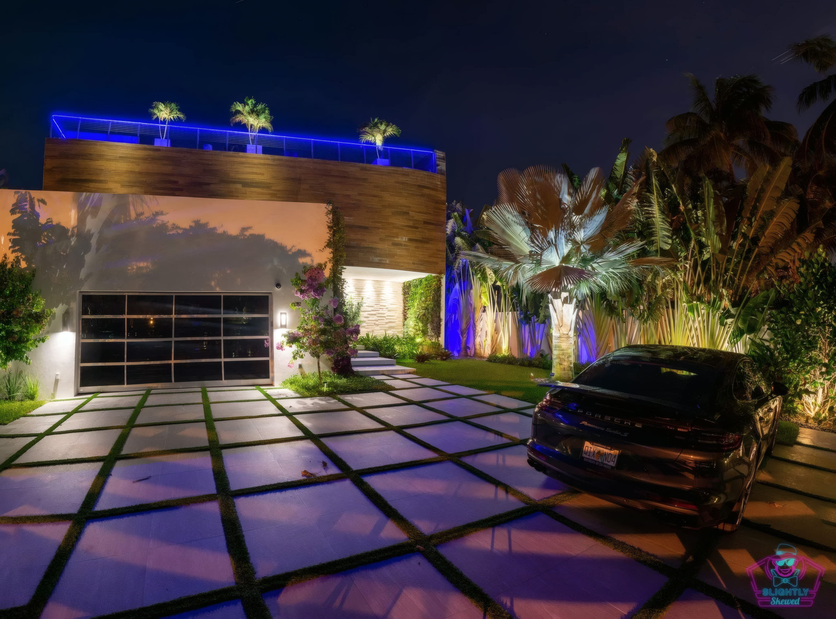 Pool house entry at twilight with custom paver driveway and uplit Bismarck palms