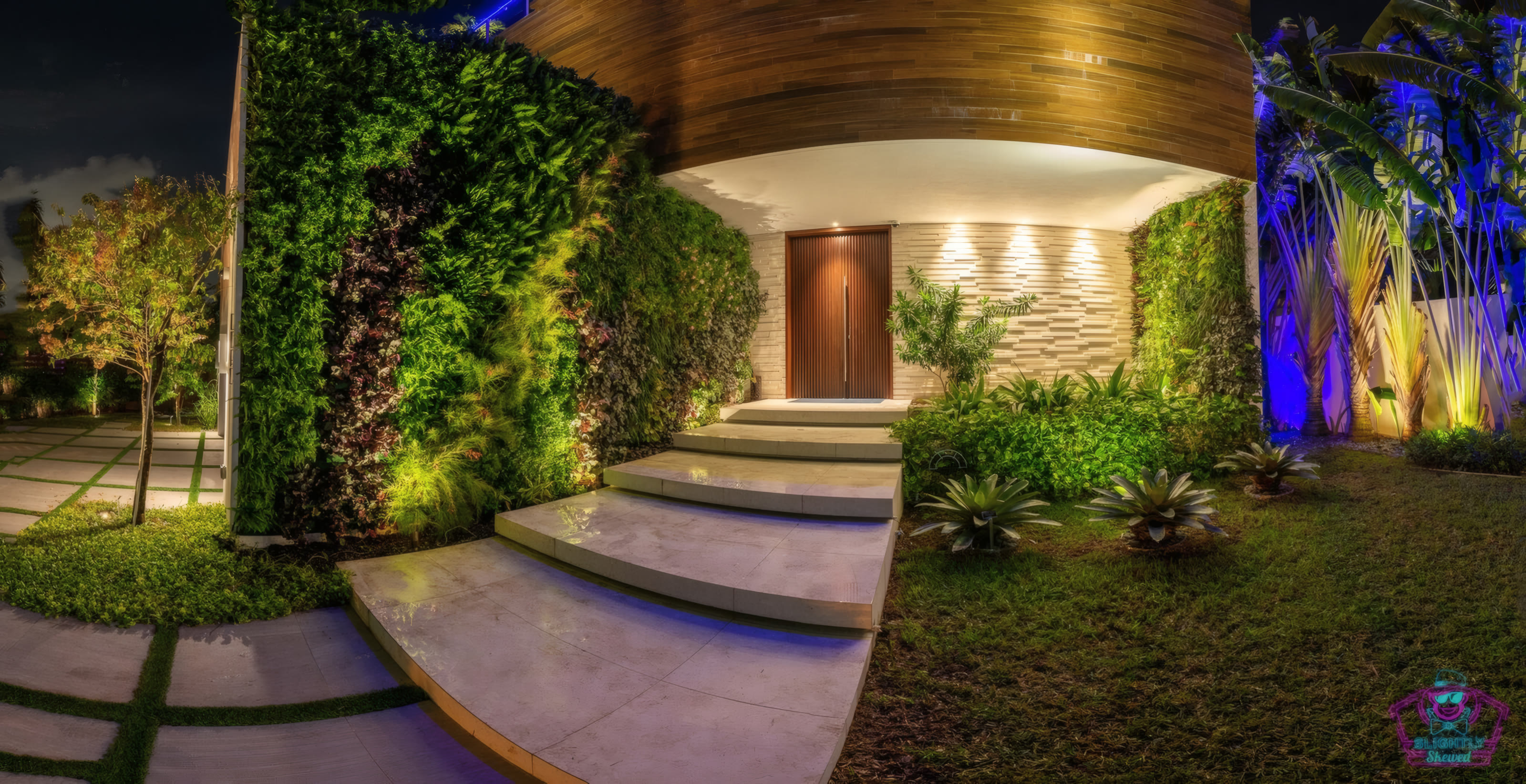 Curved sculptural pavilion entry at night with vertical garden walls and cascading limestone steps