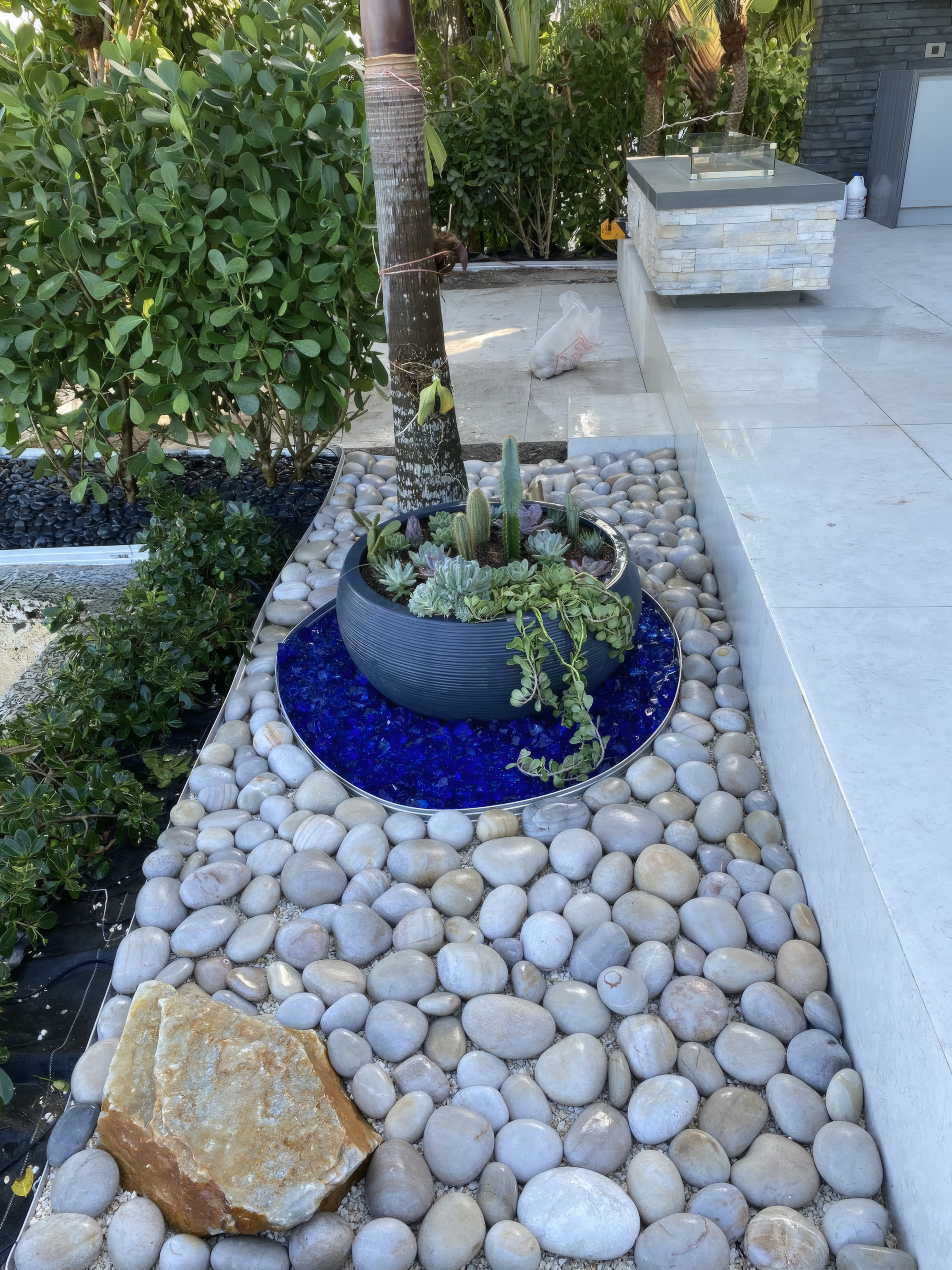 Pool deck planter with succulents, river stones, and accent lighting